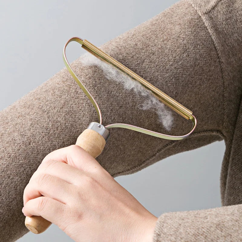 Brosse anti-poils à tête cuivre passée sur un manteau en laine, peluches retirées visibles
